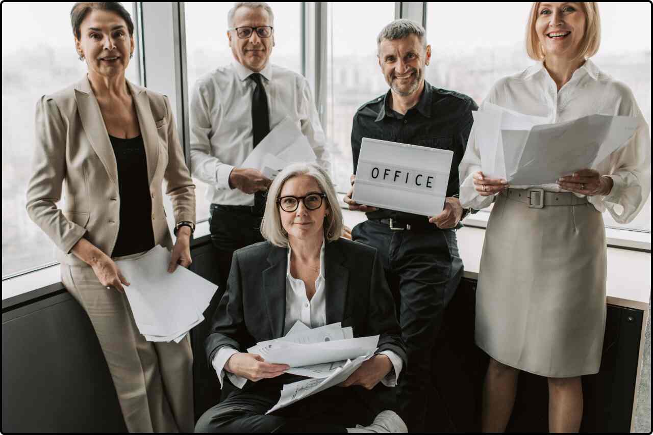 Team of corporate professionals in formal attire, standing with paperwork in hand.